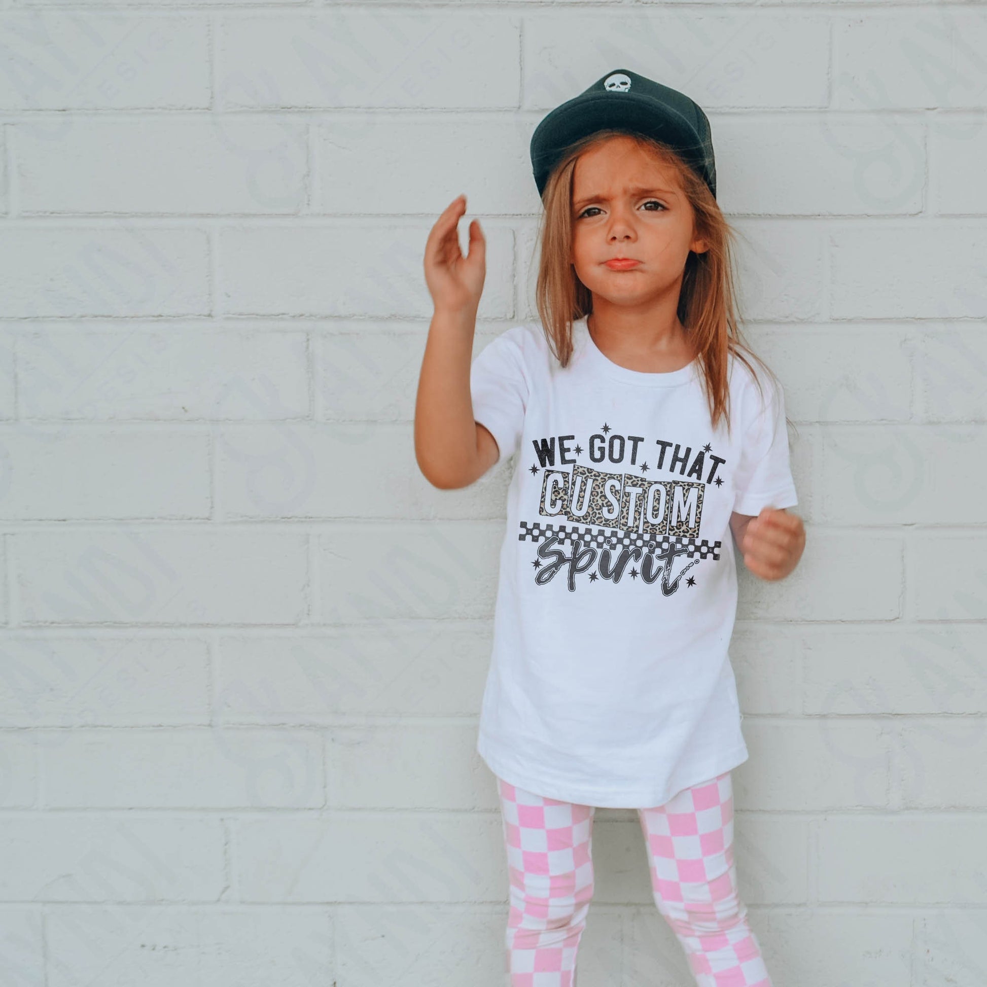 a little girl wearing a white shirt and pink checkered pants